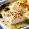 Baked cod fillet in coconut lemon cream sauce served on a plate