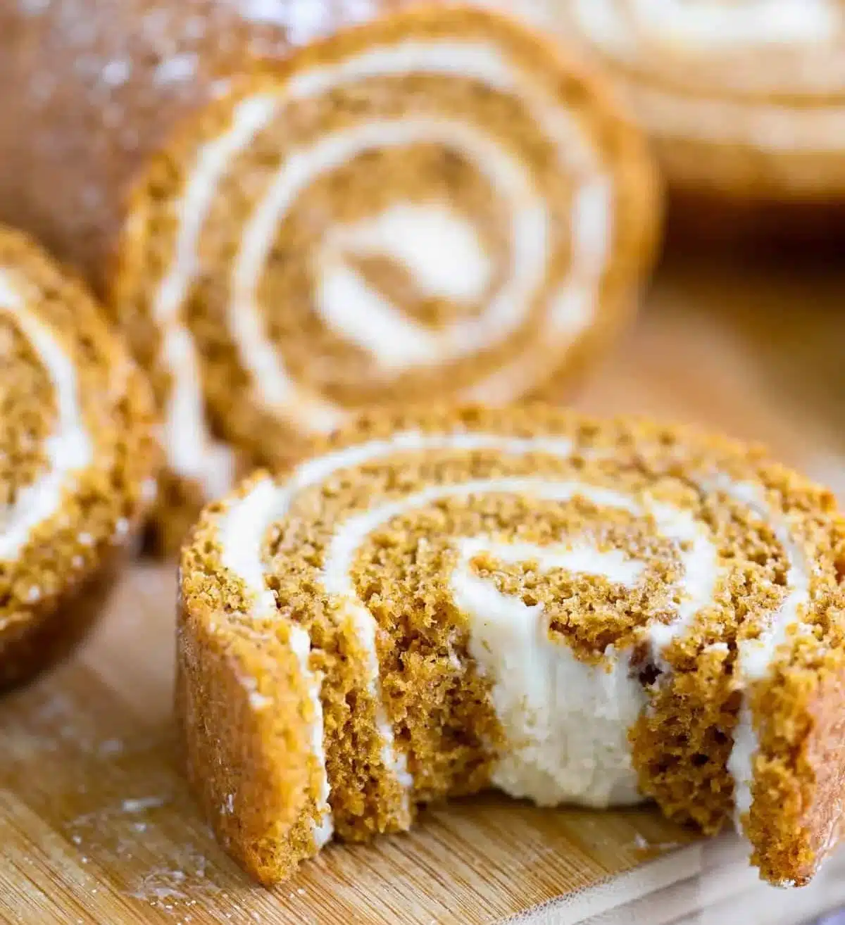 Homemade pumpkin roll with cream cheese filling on a rustic wooden table