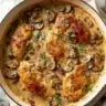 Creamy mushroom chicken dish garnished with herbs on a plate