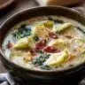 Bowl of Lemony Tuscan Artichoke Soup garnished with herbs and lemon.