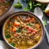Bowl of hearty Mediterranean Lentil Soup garnished with fresh herbs.