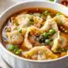 Bowl of homemade potsticker soup with dumplings and green onions